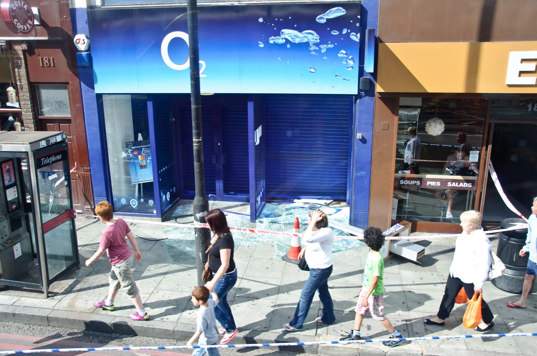 Vitrine brisée d’un commerce O2 à Camden, avec débris de verre et périmètre de sécurité