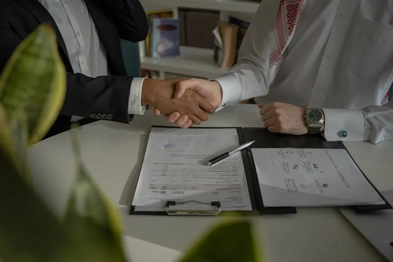 Poignée de main au-dessus de documents pour préparer la cession d’une entreprise